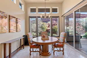 Tiled dining room with a high ceiling, a healthy amount of sunlight, and an inviting chandelier