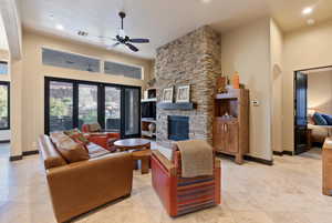 Living room featuring ceiling fan and a stone fireplace