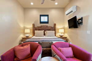 Bedroom featuring a wall mounted air conditioner and ceiling fan