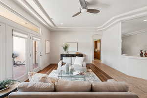 Living room with hardwood / wood-style flooring, ceiling fan, and a tray ceiling