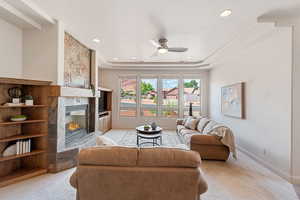 Carpeted living room featuring a tiled fireplace and ceiling fan