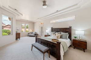 Bedroom featuring a raised ceiling, light colored carpet, and ceiling fan