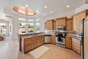 Kitchen featuring sink, a tray ceiling, kitchen peninsula, stainless steel appliances, and backsplash