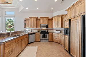 Kitchen featuring light tile patterned flooring, stainless steel appliances, kitchen peninsula, and backsplash