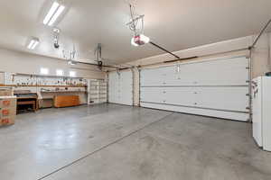 Garage with a garage door opener, a baseboard heating unit, and white refrigerator