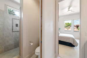 Bathroom featuring tiled shower, ceiling fan, and toilet