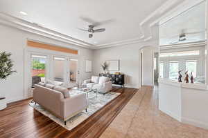 Tiled living room with ceiling fan, a tray ceiling, and a healthy amount of sunlight