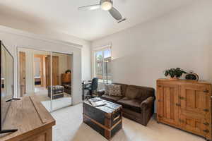 Carpeted living room featuring ceiling fan