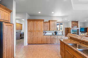 Kitchen with sink, washer and dryer, light tile patterned floors, a tiled fireplace, and decorative backsplash