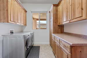 Washroom featuring cabinets, separate washer and dryer, and light tile patterned floors