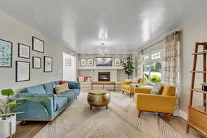 Living room with wood-type flooring, a chandelier, and a textured ceiling