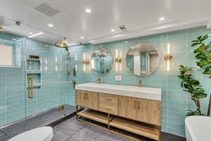 Bathroom with vanity, toilet, tile walls, and walk in shower