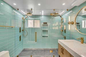 Bathroom featuring vanity, toilet, tile walls, and walk in shower