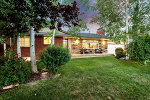 Back house at dusk featuring a yard and a garage