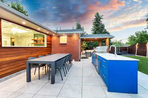 Patio terrace at dusk with exterior kitchen and an outdoor bar