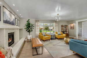 Living room with a high end fireplace, a chandelier, and light wood-type flooring