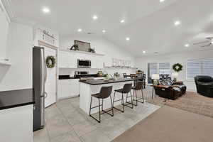 Kitchen with stainless steel appliances, white cabinetry, a breakfast bar area, and light tile patterned floors