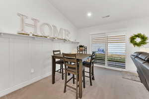 Carpeted dining area featuring vaulted ceiling