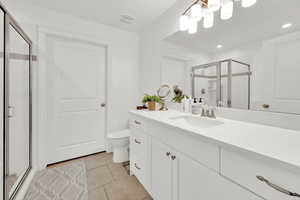 Bathroom featuring vanity, a notable chandelier, a shower with shower door, tile patterned floors, and toilet