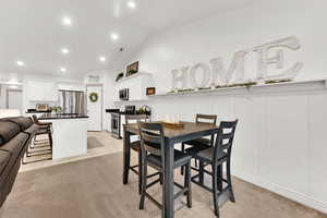 Dining room with lofted ceiling and light carpet