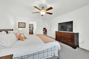 Carpeted bedroom featuring ceiling fan and ensuite bathroom