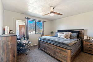 Carpeted bedroom with a textured ceiling and ceiling fan