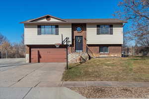 Bi-level home featuring a garage and a front yard