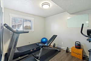 Workout area featuring dark wood-type flooring and a textured ceiling