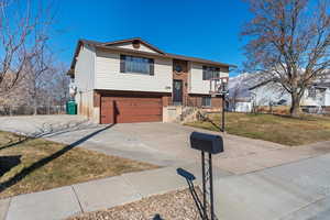 Raised ranch featuring a garage and a front lawn