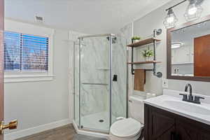 Bathroom with hardwood / wood-style flooring, vanity, toilet, and walk in shower