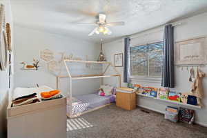 Carpeted bedroom with ceiling fan and a textured ceiling