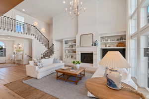 Living room with light wood-type flooring, an inviting chandelier, and built in shelves