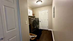 Laundry area featuring cabinets, dark hardwood / wood-style flooring, washer and dryer, and a storage closet