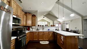 Kitchen featuring vaulted ceiling, appliances with stainless steel finishes, kitchen peninsula, pendant lighting, and decorative backsplash