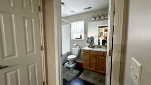 Full bathroom with vanity, hardwood / wood-style flooring, toilet, and washtub / shower combination