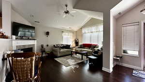 Living room with a tile fireplace, vaulted ceiling, dark hardwood / wood-style floors, and ceiling fan