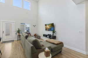 Living room featuring a towering ceiling, plenty of natural light, and laminate flooring