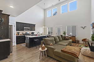 Main living area with a towering ceiling, an inviting chandelier, and light laminate / wood-style floors