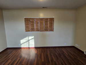 Unfurnished room with dark wood-type flooring and a textured ceiling