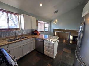 Kitchen with sink, white cabinetry, appliances with stainless steel finishes, kitchen peninsula, and pendant lighting