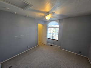 Carpeted empty room with ceiling fan and a textured ceiling