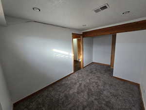 Carpeted spare room featuring a textured ceiling