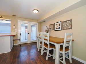 Dining space with dark wood-type flooring and french doors