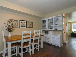 Dining area with dark hardwood / wood-style floors and a textured ceiling