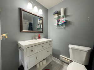 Bathroom with a baseboard heating unit, vanity, tile patterned floors, toilet, and walk in shower