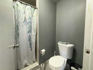 Bathroom featuring a shower with curtain, tile patterned floors, and toilet