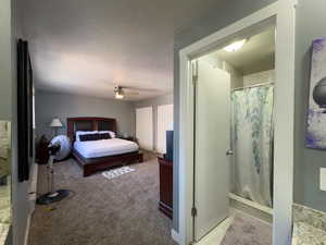 Bedroom with light carpet, a textured ceiling, and ceiling fan