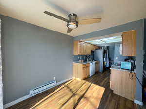 Kitchen featuring dark hardwood / wood-style floors, stainless steel fridge, ceiling fan, white dishwasher, and baseboard heating