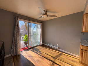 Unfurnished dining area with ceiling fan, light hardwood / wood-style floors, a textured ceiling, and a baseboard heating unit