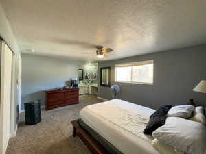 Carpeted bedroom featuring a textured ceiling and ceiling fan